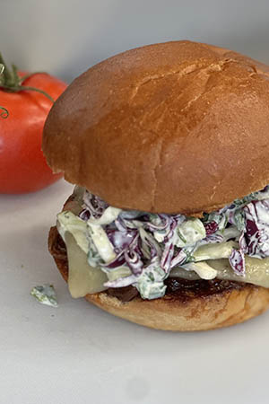 brisket sandwich with coleslaw in front of a tomato